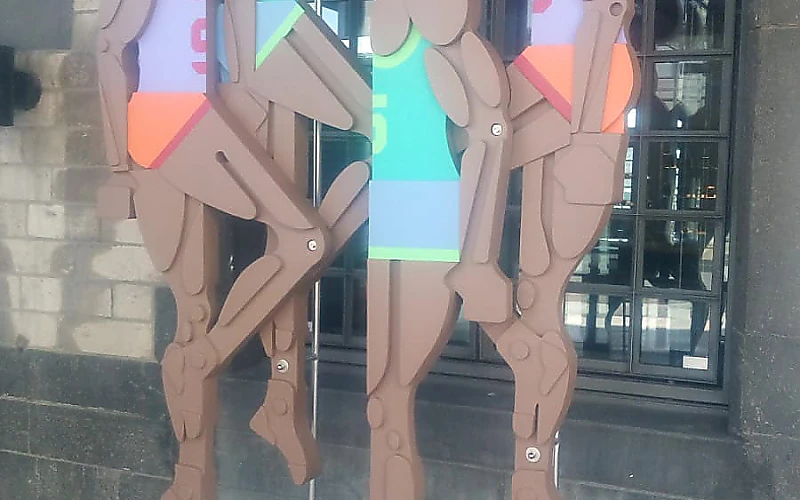 Künstlerisch gestaltete Holzfiguren mit farbigen Details an einer Fassade